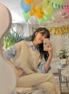teen girl wearing a cream sweater vest over a blue button-down shirt with cream slacks
